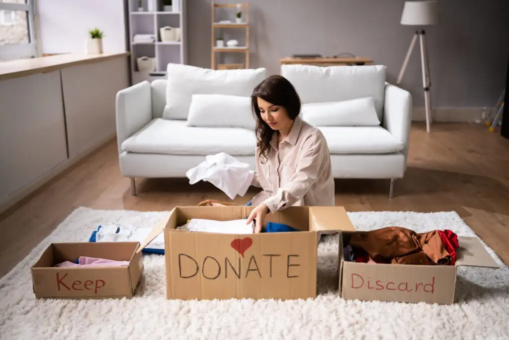 woman-decluttering-dividing-clothes-boxes - Your Savvy Purse