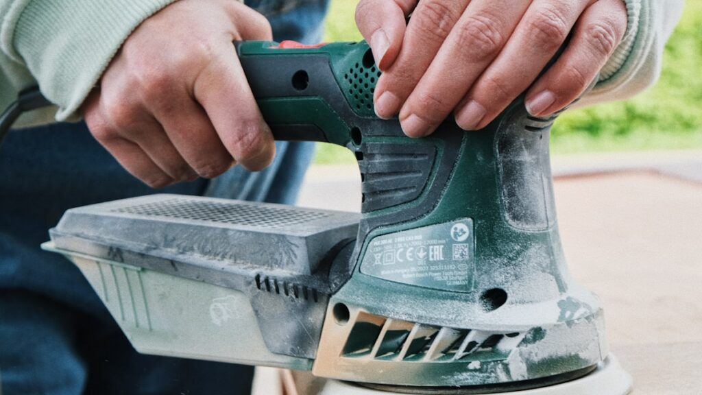 A person sanding a wooden table as part of a DIY furniture makeover