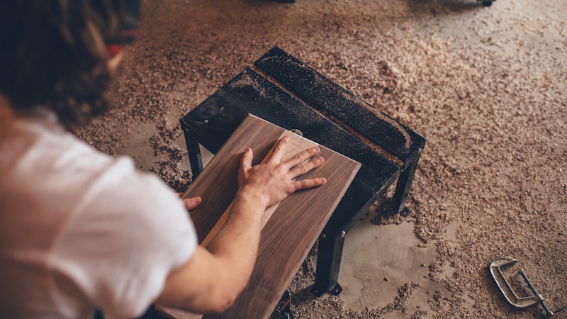 Close-up of a hand touching a wood plank during a furniture project