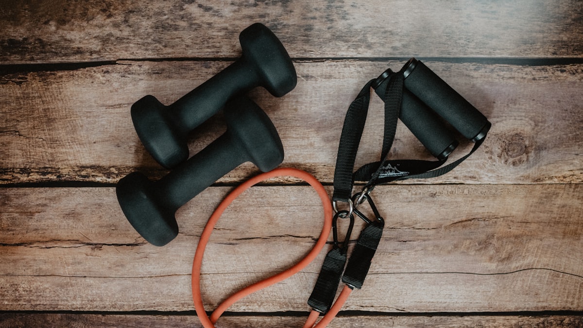Two dumbbells and a resistance band laid out for a home strength workout
