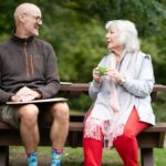A man and a woman sitting together on a park bench