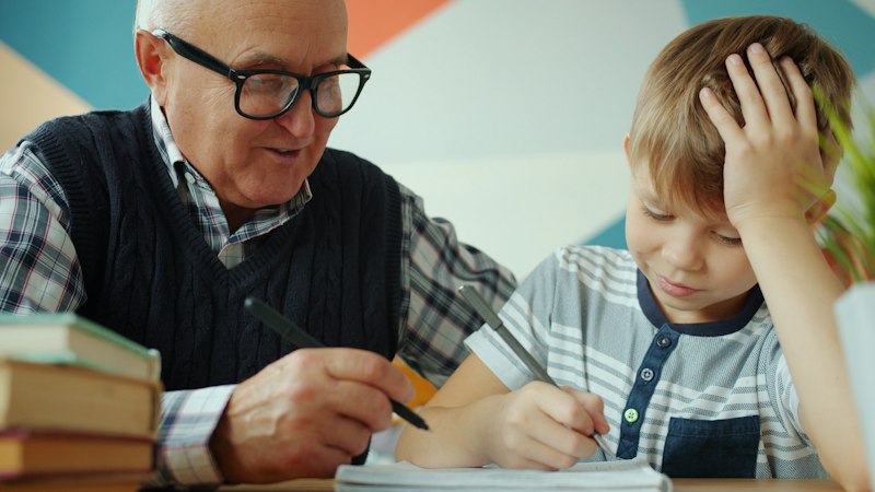 Grandfather helping grandson with homework at a table